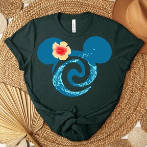 Puede incluir: Camiseta verde oscuro con una silueta azul de Mickey Mouse, una flor de hibisco y un dise&ntilde;o de agua. La camiseta est&aacute; hecha de un material suave, adecuada para uso casual.