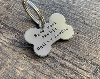 May include: Silver dog bone-shaped tag with a key ring attached. The tag has the text "Have your people call my people" engraved on it.
