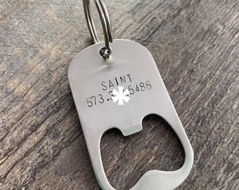 May include: Silver bottle opener keychain with a star of life symbol and the text "SAINT 573.3.5486".