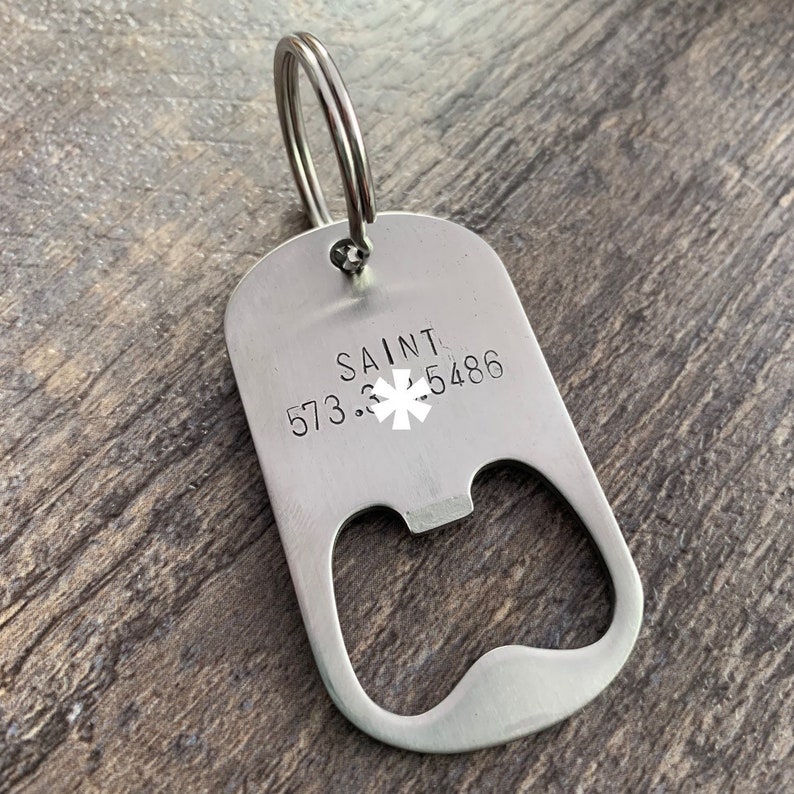 May include: Silver bottle opener keychain with a star of life symbol and the text "SAINT 573.3.5486".