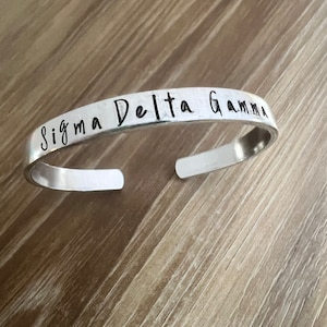 Pulsera de puño estampada a mano de hermandad o fraternidad griega