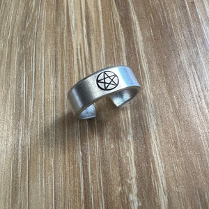 May include: A silver ring with a pentagram design engraved on the top.