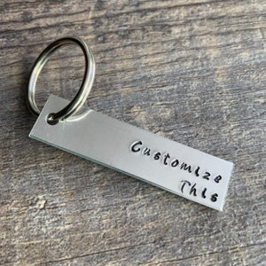 May include: Silver metal keychain with a ring and a rectangular tag that says "Customize This".