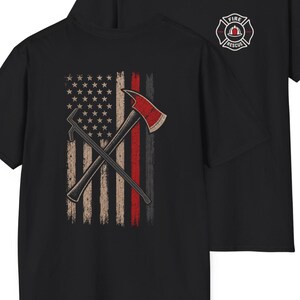 Könnte beinhalten: Ein schwarzes T-Shirt mit einem kleinen Fire Rescue-Emblem auf der Brust. Die Rückseite zeigt eine abgenutzte amerikanische Flagge mit einem dünnen roten Streifen, überlagert von einer gekreuzten Feuerwehraxt und einem Halligan-Tool.