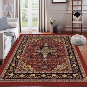 Könnte beinhalten: Ein rechteckiger roter Teppich mit einem aufwendigen, detaillierten Muster. Der Teppich hat ein zentrales Medaillon-Design in Blau-, Gold- und Cremetönen, umgeben von einem schwarzen und goldenen Rand. Er liegt auf einem Holzboden.