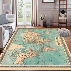 May include: A rectangular area rug featuring a vintage world map design. The rug has a light blue and beige color scheme with detailed geographical features. The border is a dark color with a Greek key pattern. The text "THE WORLD" is visible.