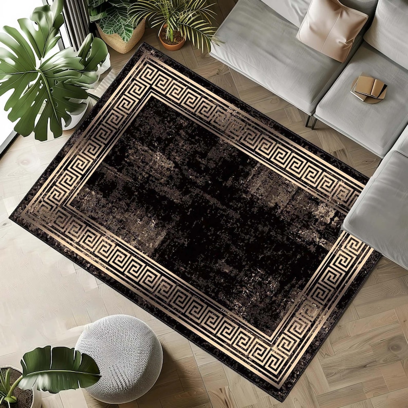 May include: A rectangular area rug with a black and brown distressed pattern. The rug features a gold Greek key border. The rug is placed on a hardwood floor, with a gray sofa and plants in the background.