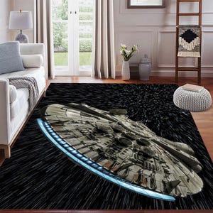 Puede incluir: Una alfombra rectangular con una ilustración detallada de una nave espacial en una escena espacial negra con rayas blancas. La nave espacial es gris con detalles azules. La alfombra está diseñada para la decoración del hogar.
