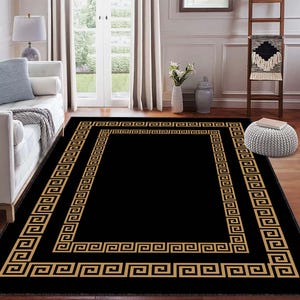 May include: A rectangular black area rug with a gold Greek key border design. The rug is placed on a hardwood floor in a living room setting. The rug's design adds a touch of elegance to the room's decor.