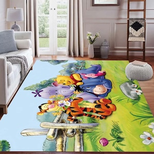 Puede incluir: Una alfombra rectangular con una ilustración de dibujos animados de Winnie the Pooh y sus amigos. La alfombra presenta un cielo azul claro, una zona de hierba verde y una valla de madera. Los personajes incluyen Winnie the Pooh, Piglet, Eeyore y Tigger.