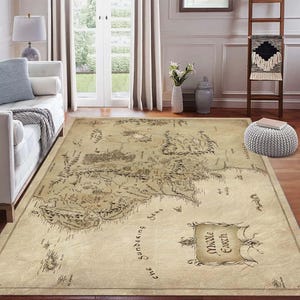 Pode incluir: Um tapete retangular com um mapa da Terra Média impresso. O tapete tem um fundo bege com um design de mapa detalhado em tons de castanho e preto. As palavras "Middle Earth" são exibidas em uma faixa decorativa.