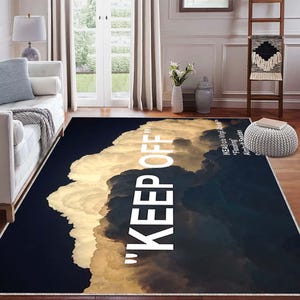 Può includere: Tappeto rettangolare con un design a nuvole nei toni del bianco, crema e blu scuro. Le parole "KEEP OFF" sono stampate verticalmente in grandi lettere bianche. Progettato per uso interno.