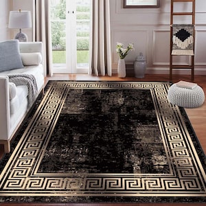 May include: A rectangular black area rug with a gold Greek key border. The rug has a distressed appearance with a dark, mottled pattern. The gold border frames the central design, adding a touch of elegance to the room.