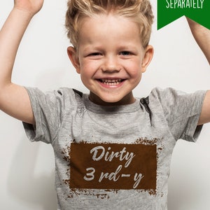 K&ouml;nnte beinhalten: Ein kleines Kind tr&auml;gt ein graues T-Shirt mit einem braunen rechteckigen Grafik, auf dem "Dirty 3 rd - y" steht.
