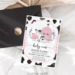 May include: A pink and white cow-themed birthday party invitation with a watercolour illustration of a cow and a red barn. The text reads "holy cow Olivia is one! please help us celebrate Saturday | June 20th | 2-4pm at the sandhill residence 1234 hilltop way, herring tn rsvp to cass @ 999.999.9999 invited by cass".