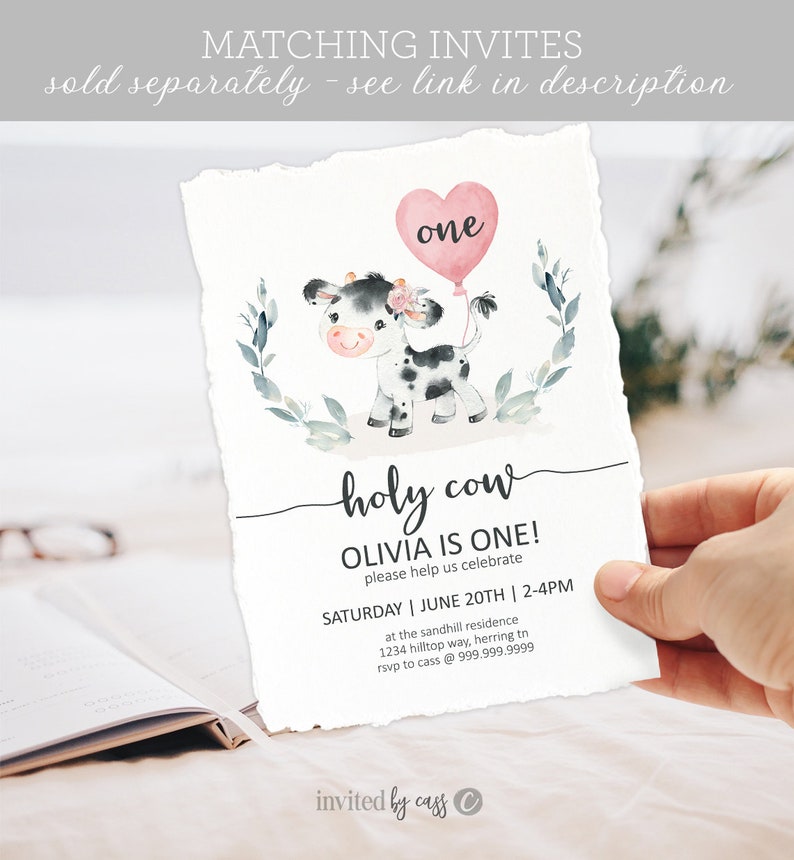 May include: A pink and white cow with a pink heart balloon that says "one" on it. The text "holy cow" is written in cursive. The text "Olivia is one!" is written in black. The text "Please help us celebrate" is written in black. The text "Saturday | June 20th | 2-4pm" is written in black. The text "at the sandhill residence" is written in black. The text "1234 hilltop way, herring tn" is written in black. The text "rsvp to cass @ 999.999.9999" is written in black. The text "invited by cass" is written in black.