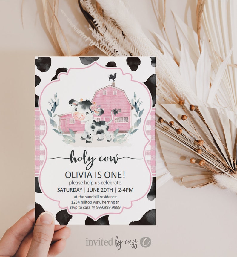May include: A pink and white cow with black spots stands in front of a pink barn with a black rooster on top. The text "holy cow" is written in black script. The text "Olivia is one!" is written in black. The text "Please help us celebrate" is written in black. The text "Saturday | June 20th | 2-4pm" is written in black. The text "at the sandhill residence" is written in black. The text "1234 hilltop way, herring tn" is written in black. The text "rsvp to cass @ 999.999.9999" is written in black. The text "invited by cass" is written in black. The text "C" is written in black.