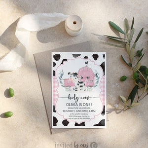 May include: A pink and black cow-print invitation with a pink and white gingham border. The invitation features a cartoon cow in front of a red barn with a black rooster on top. The text reads "holy cow Olivia is one! please help us celebrate SATURDAY | JUNE 20TH | 2-4PM at the sandhill residence 1234 hilltop way, herring tn rsvp to cass @ 999.999.9999 invited by cass".