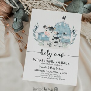 May include: A baby shower invitation with a watercolor illustration of a black and white cow in front of a blue barn. The text "holy cow" is written in a whimsical font. The invitation reads "We're having a baby! Please help us celebrate Amanda & Baby Jackson. Saturday, Aug 20th, 2-4pm. 1234 Hilltop Way, Herring TN. RSVP to Cass @ 999.999.9999. Registry: Amazon, Buy Buy Baby, & Target. Invited by Cass."