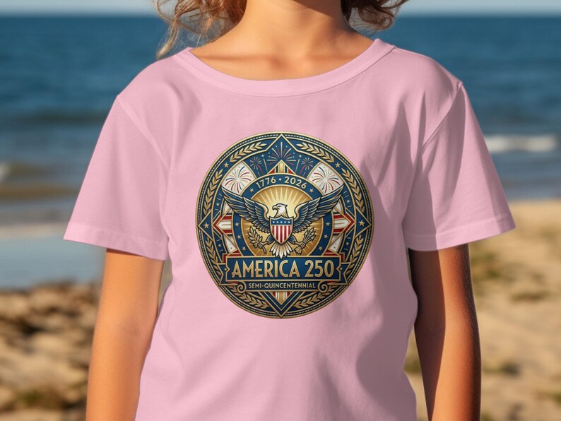 Pink t-shirt with circular patriotic emblem featuring eagle, stars, and "America 250".