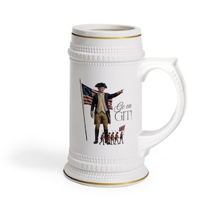 Puede incluir: Jarra de cerveza de cerámica blanca con borde y asa dorados. La jarra presenta una imagen de un hombre con uniforme colonial señalando con el texto "Go on GIT!" y una bandera americana.