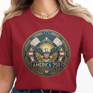 Red t-shirt with "America 250 Semi-Quincentennial" logo featuring an eagle and stars.