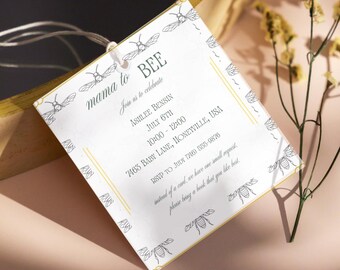 May include: A white invitation card with the text "mama to BEE" and bee illustrations. The card includes event details: Ashlee Bensin, July 6th, 10:00-12:00, and a Honeyville, USA address. The card also requests a book instead of a card.