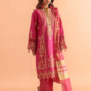 May include: A vibrant pink embroidered outfit, featuring a long-sleeved tunic and matching pants. The tunic is adorned with intricate gold embroidery, and the outfit includes a coordinating scarf. The ensemble is a traditional style.