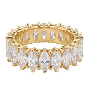 May include: A gold-colored ring with a continuous band of marquise-cut, clear gemstones. The ring's band is also gold-colored, with a smooth, polished finish. The gemstones are set closely together, creating a sparkling effect.