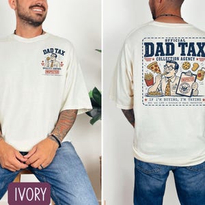 May include: Ivory-colored t-shirt with "DAD TAX" graphic on the front and back. The front graphic includes text "QUALITY CONTROL INSPECTED". The back graphic reads "OFFICIAL DAD TAX COLLECTION AGENCY" with the phrase "IF I'M BUYING, I'M TRYING".