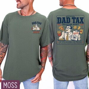 May include: Moss green t-shirt with a graphic on the front and back. The front graphic says "DAD TAX" with a cartoon image. The back graphic says "OFFICIAL DAD TAX COLLECTION AGENCY" with a cartoon image of a man eating food.