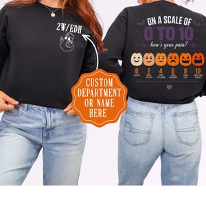 May include: A black long-sleeve sweatshirt featuring a small white ghost graphic on the front chest with the text 2W/EDH. The back displays a pain scale graphic with six pumpkins showing different expressions and the text ON A SCALE OF 0 TO 10 how's your pain?