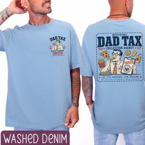 May include: Light blue t-shirt with the text "DAD TAX" and a cartoon graphic on the front and back. The back graphic reads "OFFICIAL DAD TAX COLLECTION AGENCY" with a cartoon man eating pizza and fries. The shirt is labeled "WASHED DENIM".