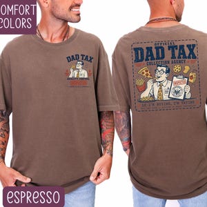May include: Espresso-colored t-shirt with the text "DAD TAX" and a cartoon graphic on the front and back. The back graphic reads "OFFICIAL DAD TAX COLLECTION AGENCY" with an illustration of a man eating fast food. The shirt is a comfort color.