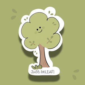May include: A sticker featuring a cartoon tree with a smiling face and the text "Just beLEAF!". The tree has a light green crown, a brown trunk, and a small patch of green grass at the base. The background is a solid light green.