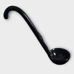 May include: A black ladle with a curved handle and a round bowl. The ladle is made of a glossy material, designed for serving soups or sauces. The handle has a hook for hanging, and the ladle is suitable for kitchen use.