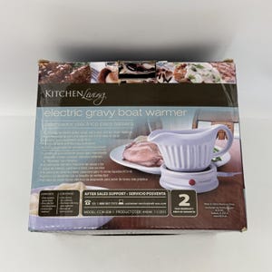 K&ouml;nnte beinhalten: Ein elektrischer So&szlig;enw&auml;rmer von Kitchen Living in einem Karton. Die Verpackung zeigt eine wei&szlig;e Keramik-So&szlig;enschale mit geripptem Design auf einer W&auml;rmestation sowie Text mit einer Kapazit&auml;t von 473 ml und einer 2-j&auml;hrigen Garantie.