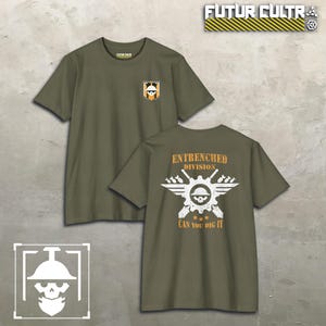May include: An olive green short-sleeve t-shirt featuring a small logo on the front chest and a large graphic on the back. The back design displays a white skull wearing a helmet, crossed shovels, wings, and the text "ENTRENCHED DIVISION CAN YOU DIG IT".