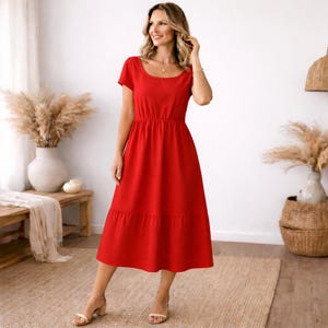 Peut inclure: Une robe midi rouge vif avec un col rond et des manches courtes. La robe a une taille ajust&eacute;e et une jupe &agrave; volants, cr&eacute;ant une silhouette fluide. La mod&egrave;le porte des sandales.