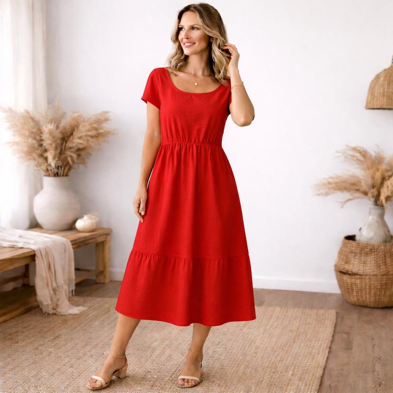 Peut inclure: Une robe midi rouge vif avec un col rond et des manches courtes. La robe a une taille ajust&eacute;e et une jupe &agrave; volants, cr&eacute;ant une silhouette fluide. La mod&egrave;le porte des sandales.