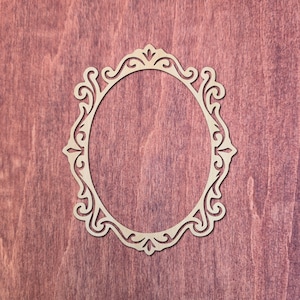 May include: A light beige, oval-shaped wooden frame cutout featuring intricate, symmetrical scrollwork and filigree patterns along the outer border. The frame has a smooth, flat surface and a hollow center, showcasing a detailed, ornate design.