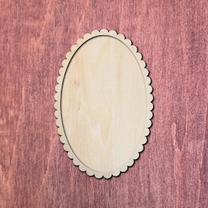 May include: An oval-shaped wooden cutout featuring a scalloped edge. The surface of the wood is light beige with a visible natural grain pattern, and the scalloped border consists of a series of small, rounded semi-circles around the perimeter.