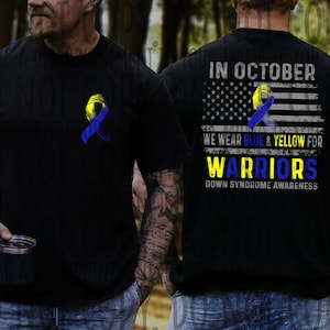 May include: Black t-shirt with a blue and yellow ribbon graphic on the front and back. The back of the shirt features an American flag design with the text "In October We Wear Blue & Yellow For Warriors Down Syndrome Awareness."