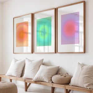 Puede incluir: Tres impresiones art&iacute;sticas enmarcadas con dise&ntilde;os de gradiente de color en tonos naranja, verde y rosa. Las impresiones se exhiben sobre un banco de madera con cojines color crema y una cesta tejida. Los marcos tienen un acabado de madera natural.