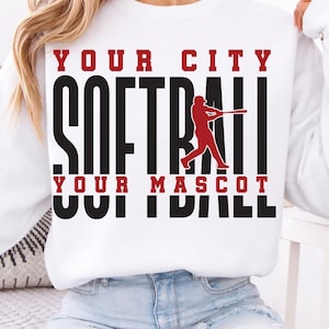 May include: White sweatshirt with the text "YOUR CITY SOFTBALL YOUR MASCOT" in black and red. A red softball player graphic is in the center. The sweatshirt is a long-sleeved crew neck.