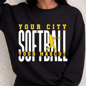 May include: Black sweatshirt with the words "YOUR CITY SOFTBALL YOUR MASCOT" in white and yellow block letters. A yellow softball player graphic is on the right side of the word "SOFTBALL".