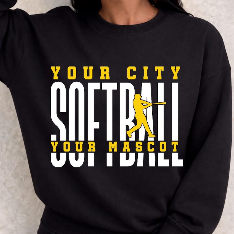 May include: Black sweatshirt with the words "YOUR CITY SOFTBALL YOUR MASCOT" in white and yellow block letters. A yellow softball player graphic is on the right side of the word "SOFTBALL".
