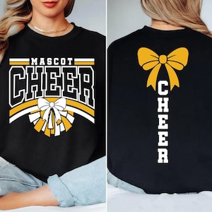May include: Black sweatshirt with "MASCOT CHEER" in white and gold lettering. A white and gold bow and pom-pom graphic is centered on the front. The back features a gold bow and the word "CHEER" in white.