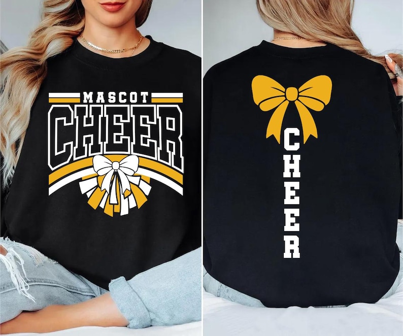 May include: Black sweatshirt with "MASCOT CHEER" in white and gold lettering. A white and gold bow and pom-pom graphic is centered on the front. The back features a gold bow and the word "CHEER" in white.