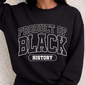 May include: Black sweatshirt with white text that reads "PRODUCT OF BLACK HISTORY" in a bold, collegiate-style font. The sweatshirt is a crew neck style, and the text is centered on the chest.